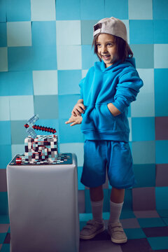 fashion boy in blue clothes bites at a cake pixels with pickaxe in the studio. birthday five years
