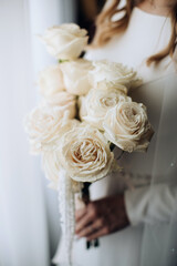 The bride holds a wedding bouquet of white roses