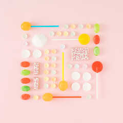 Creative arrangement made of candies in the shape of a square on a pink background. Minimal lollipops, candies and sugar concept. Flat lay.