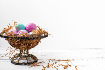 Silk-Dyed Easter Eggs in a Wire Basket on a White Background