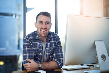 Doing what I love and making money from it. Portrait of a happy young businessman working at his office desk.