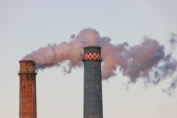 Big factory chimneys polluting the atmosphere in twilight light. Thermal power plant chimney shell.