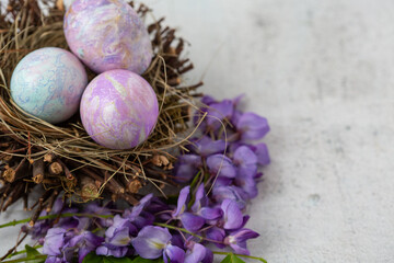 Easter Eggs Dyed with Various Patterns of Purple Silk in a Nest Surrounded by Purple Wisteria on a White Background
