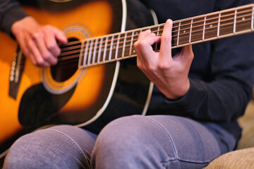 Fototapeta na wymiar Close up of young student boy hands playing classic guitar at home. Teen leisure and music art activity background.