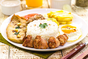 plate with typical Brazilian meal, sausage and fried chicken, rice with beans and salad, farofa and fried egg