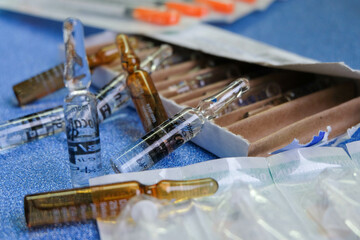 Medical ampoules full of medicine and their box on a blue background
