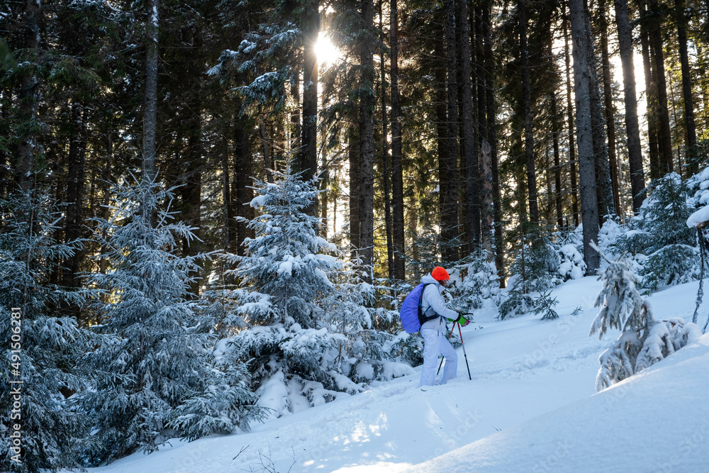 Wall mural portrait of a young white caucasian female hiker dressed in white climbing the uphill full of snow