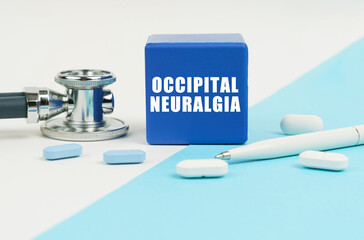 On a white and blue surface are pills, a stethoscope, a pen and a cube with the inscription -...
