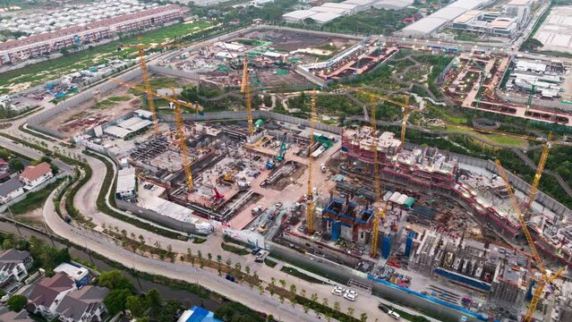 Hyperlapse time-lapse of under construction site project, crane transportation at night in Asia city. Drone aerial view. Industrial business or civil engineering technology concept