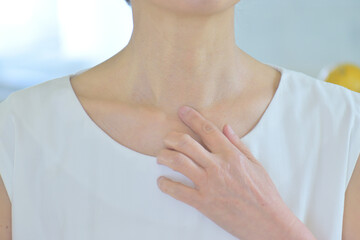 デコルテを手で触る女性