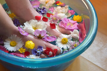 Obraz na płótnie Canvas Flowery foot bath with wild flowers. Skin softening floral foot soak. A footbath is a lovely way to still life for ten minutes. Get a luxurious spa-quality pedicure in the comfort of your own home