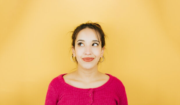 Young African Woman Looking Away From Camera Naughty Thinking About Something, Posing Isolated Over Yellow Color Wall Background. Daily Expressions With Copy Space In Studio.