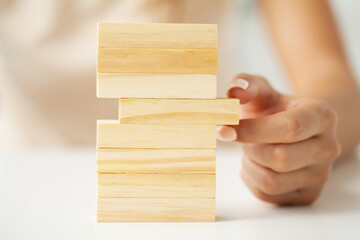 Hand picking up one wooden cube on table background.
