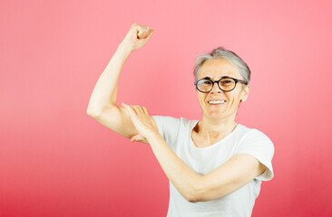 Old woman grabbing her arm muscle with strong attitude, woman power and feminism concept posing...