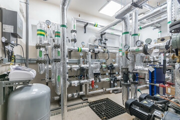 A modern gas boiler room with a system of pipes, pressure gauges, sensors and valves.