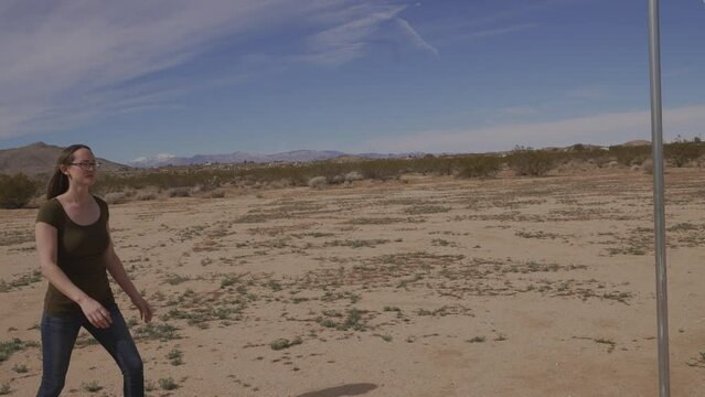 This video shows a woman playing tether ball in a secluded desert scene.