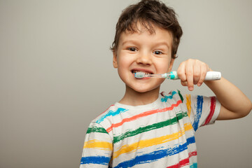 the child brushes his teeth. a boy with a toothbrush in his hands shows how to brush his teeth.