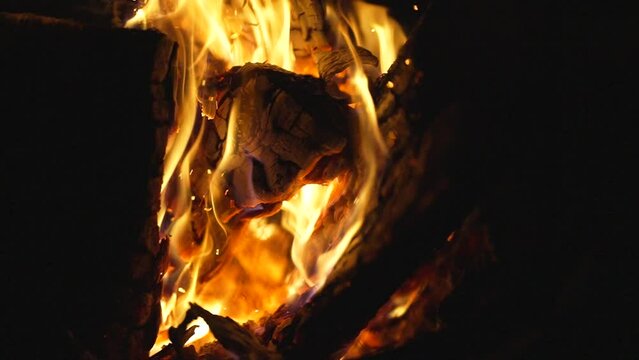 This close up video shows moody burning wood with exploding embers in super slow motion.