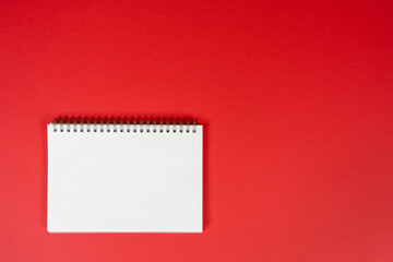 a blank spiral notebook on a red background	