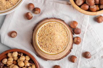 Raw Organic Ground Hazelnut Flour in a Bowl with whole nuts on grey stone background. Alternative nut flour for keto diet and gluten free food. Paleo and ketogenic diet baking cooking concept above