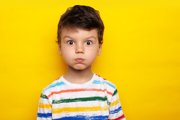 Handsome caucasian child wearing casual white T-shirt with bright stripes puffing cheeks with funny face. mouth inflated with air, crazy expression. - obrazy, fototapety, plakaty