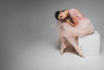 young pretty, fragile, beautiful ballerina dancing in a long pale pink dress with a tulle on a uniform background, hand movements, restrained tone. Ballet, dance, dancer. Place for inscription
