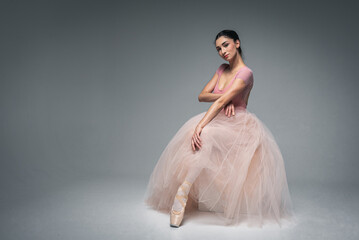 young pretty, fragile, beautiful ballerina dancing in a long pale pink dress with a tulle on a uniform background, hand movements, restrained tone. Ballet, dance, dancer. Place for inscription - obrazy, fototapety, plakaty