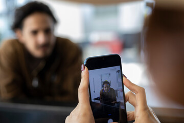 Young Latin American woman (22) on vacation taking a picture of her partner. Vacation concept