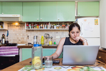 front view of young caucasian woman studying from home with her computer