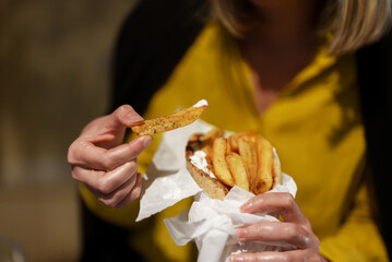 Woman eats pita with french fries.