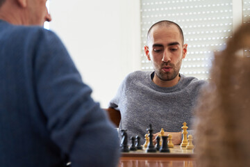 Doubt and strategy concept. Young man meditates about next move in chess game