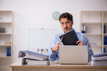 Young male employee unhappy with excessive work in the office