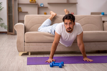 Fototapeta premium Young man doing sport exercises at home