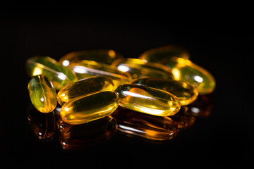 Close up of Omega 3 gel capsule on a reflective black background