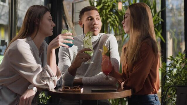 Three multiracial friends in a bar. After work party with cocktails after successful work day..