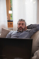 portrait d'un homme de 50 ans souriant et détendu qui travaille tranquillement avec son ordinateur...