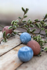 Colored Easter eggs and willow on  wooden background .