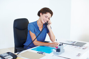 Shes hard at work. Shot of a businesswoman talking on the phone while working at her office desk.
