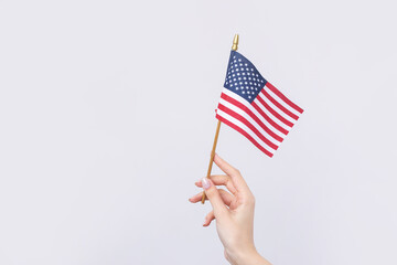 A beautiful female hand holds an American flag on a white background.