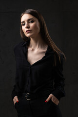 Portrait of a young brunette with long hair in the studio. Dramatic photo in dark colors.