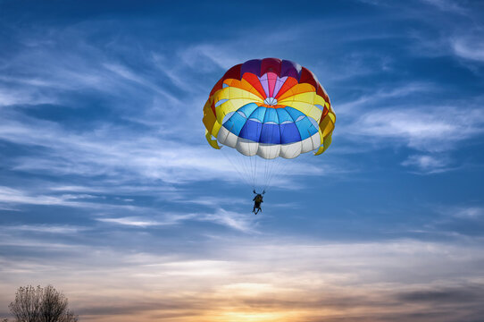 Gliding with a parachute on the background of bright sunset.