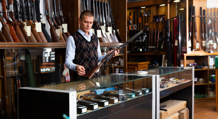 Adult owner of the gun shop demonstrates a rare collectible hunting rifle