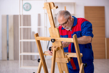 Old male carpenter repairing drawing easel