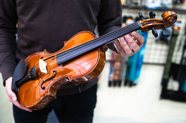 music store salesman holding a violin in his hands.