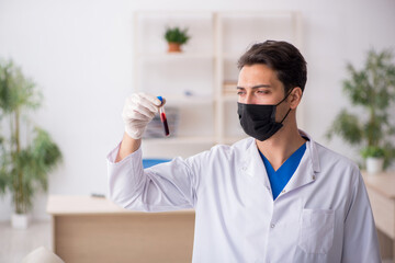 Young male chemist in pandemic concept