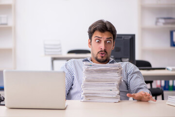 Obraz premium Young male employee and too much work in the office