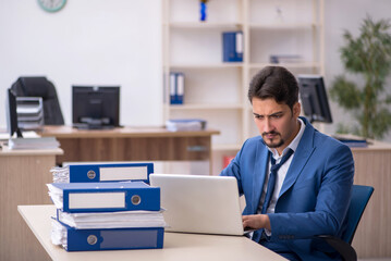 Young businessman employee unhappy with excessive work in the of