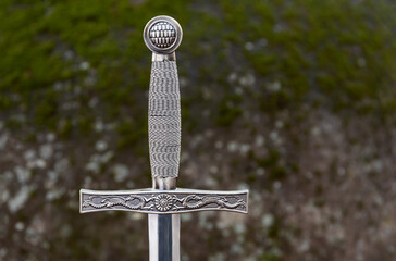 Medieval Sword with Mossy Rock Background