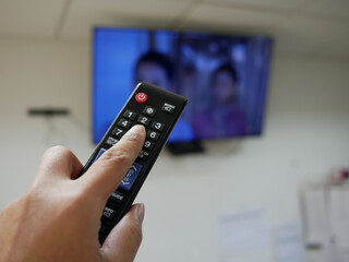 closeup of hand with the remote control television and presses the button.	
