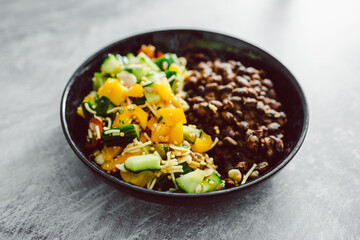 vegan mexican bowl with spicy bean mix and bell pepper cucumber salad, healthy plant-based food